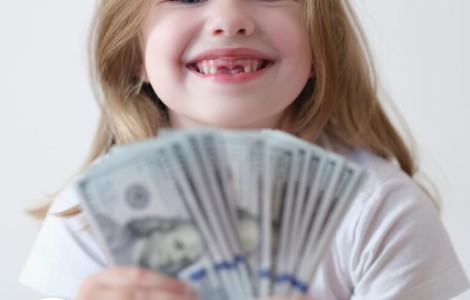 little girl smiling while holding handful of $100 bills