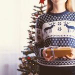 woman in holiday sweater holding gift