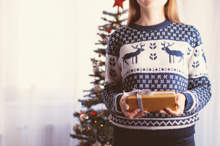 woman in holiday sweater holding gift