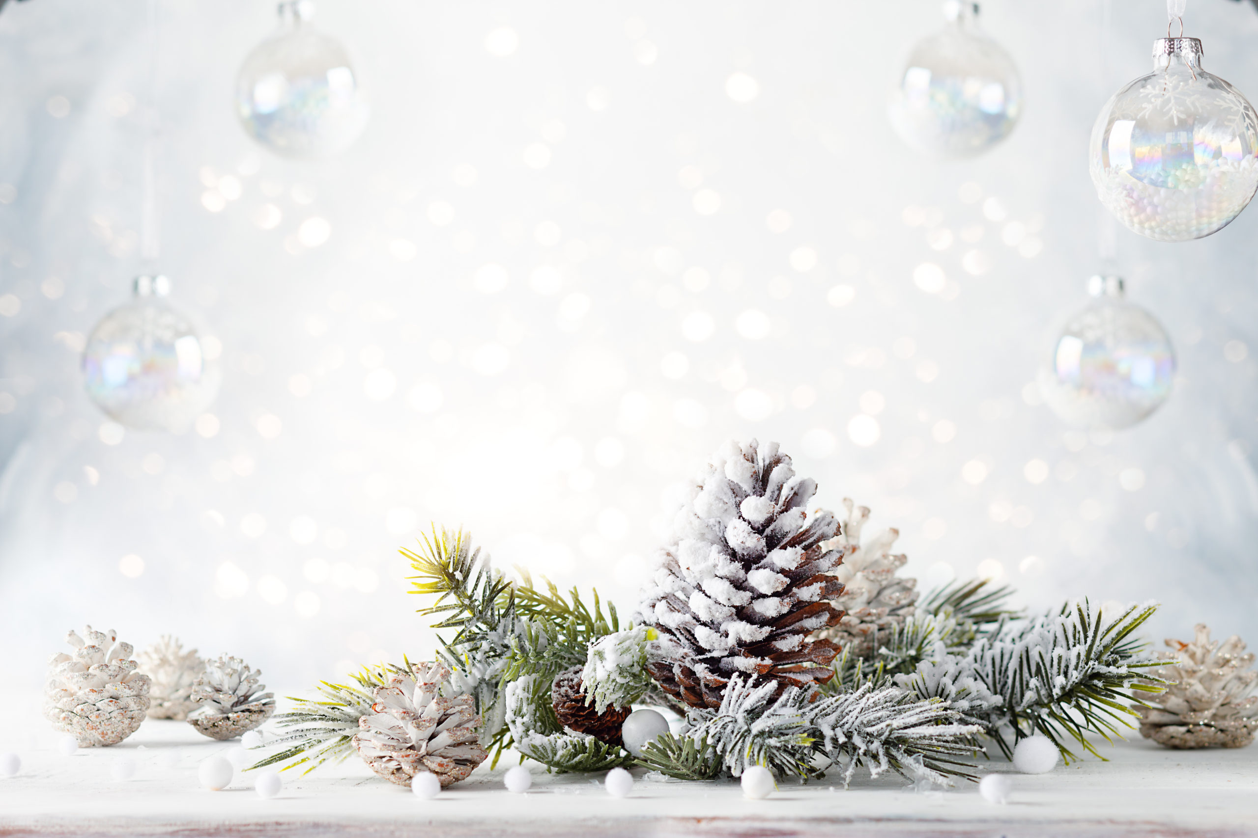 Christmas still life with snowy pine cones, baubles and  fir branches on light background.