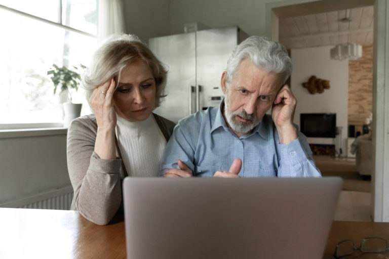 mature couple looking at computer distressed